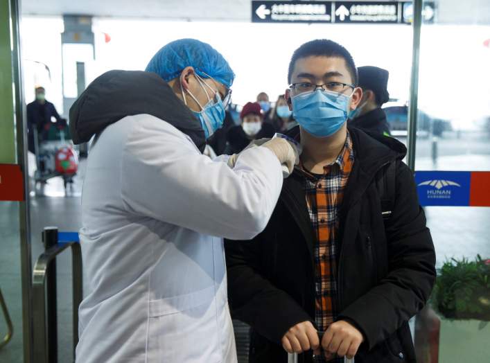 A medical official takes the body temperature of a man at the departure hall of the airport in Changsha, Hunan Province, as the country is hit by an outbreak of a new coronavirus, China, January 27, 2020. REUTERS/Thomas Peter