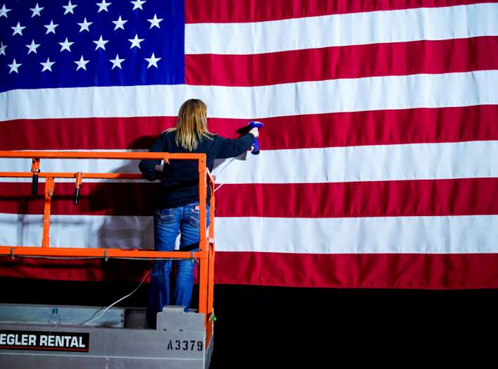 A woman takes the wrinkles from a flag before Pete Buttigieg, Democratic presidential candidate and former South Bend, Indiana mayor attends a watch party on Caucus Day in Des Moines, Iowa, U.S., February 3, 2020. REUTERS/Eric Thayer