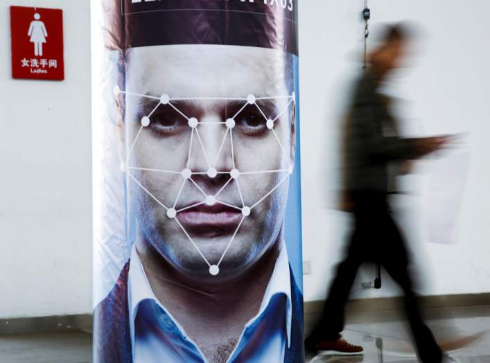 A man walks past a poster simulating facial recognition software at the Security China 2018 exhibition on public safety and security in Beijing, China October 24, 2018. REUTERS/Thomas Peter