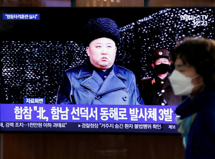 A woman walks past a TV broadcasting file footage for a news report on North Korea firing an unidentified projectile, in Seoul, South Korea, March 9, 2020. REUTERS/Heo Ran