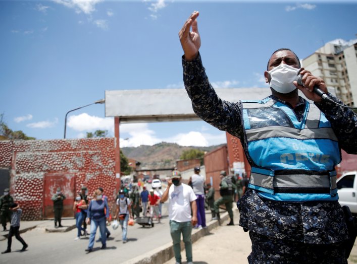 A member of the Bolivarian national police at the gates of a public market asks people to return to their homes during the national quarantine in response to the spread of coronavirus disease (COVID-19) in Caracas, Venezuela, March 21, 2020. REUTERS/Manau