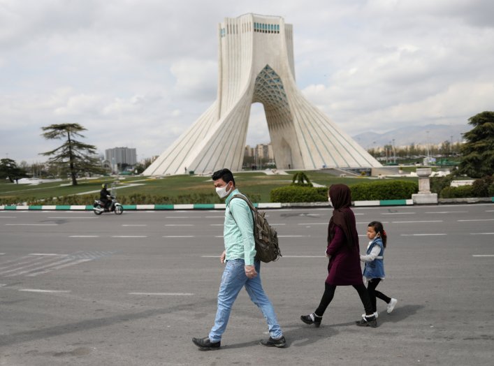 A family wear protective face masks and gloves, amid fear of coronavirus disease (COVID-19), as they walk by the iconic Freedom Square, in Tehran, Iran March 26, 2020. WANA (West Asia News Agency)/Ali Khara via REUTERS