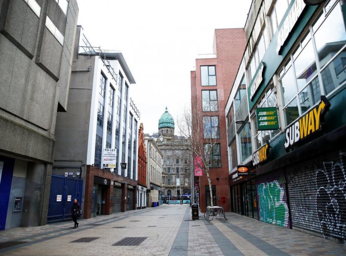 A woman walks by some businesses that remain closed as the spread of the coronavirus disease (COVID-19) continues, Belfast, Northern Ireland March 30, 2020. REUTERS/Jason Cairnduff