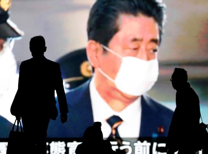 Passersby are silhouetted in front of a giant screen reporting Japan's Prime Minister Shinzo Abe and Japan's response to the coronavirus disease (COVID-19) outbreak in Tokyo, Japan April 7, 2020. REUTERS/Issei Kato
