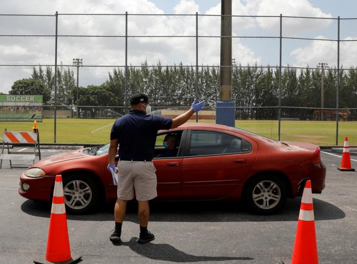 A worker controls the traffic as people in cars wait in line to pick up receiving an unemployment forms, as the outbreak of coronavirus disease (COVID-19) continues, in Hialeah, Florida, U.S., April 8, 2020. REUTERS/Marco Bello