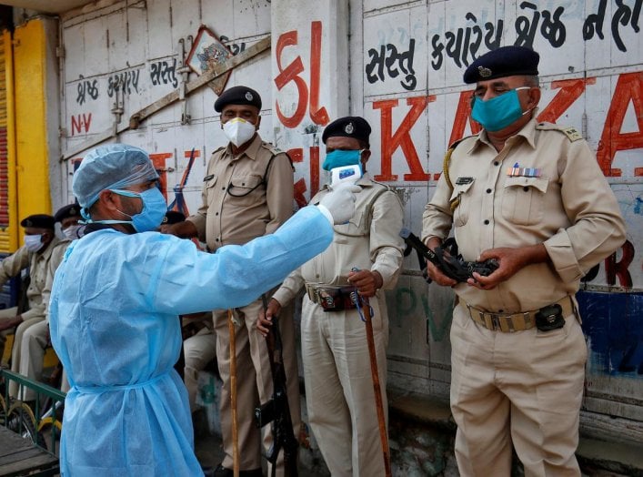 A paramedic uses an infrared thermometer to measure the temperature of a police officer alongside a road during a 21-day nationwide lockdown to slow the spreading of coronavirus disease (COVID-19) in Ahmedabad, India, April 9, 2020. REUTERS/Amit Dave
