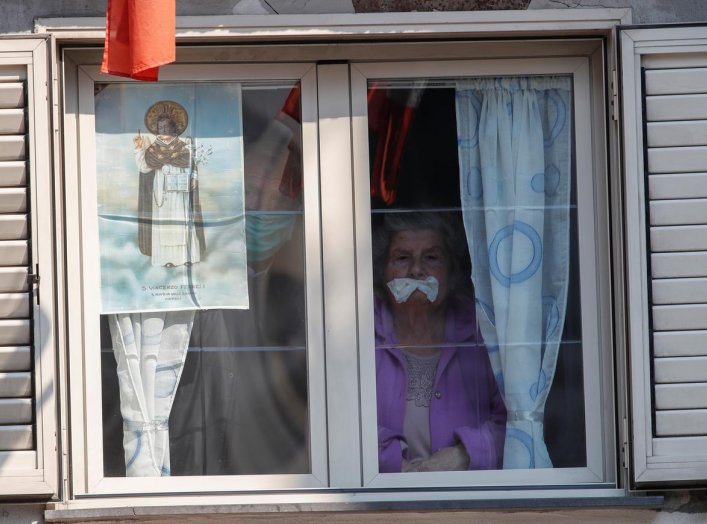 People observe from their window a crucifix displayed outside the Santa Maria della Sanita church during Good Friday, as Italy remains on lockdown during the Easter period to try and contain the spread of coronavirus disease (COVID-19), in Naples, Italy A