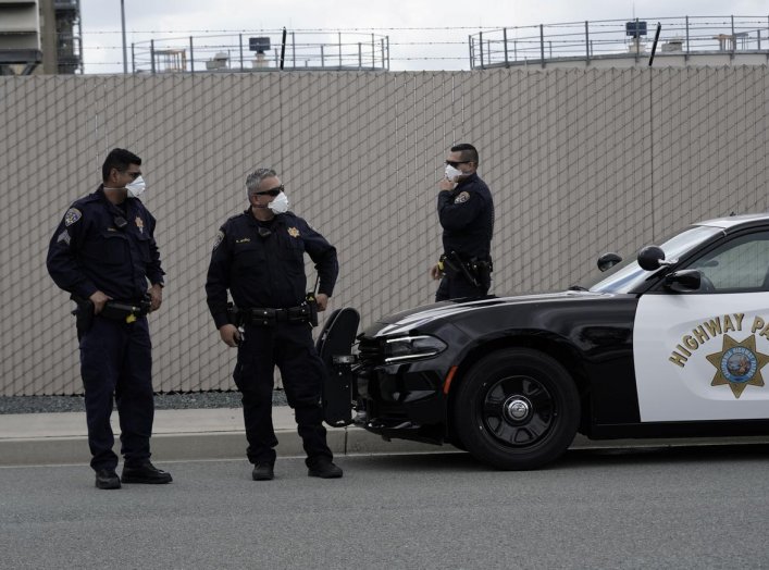 California Highway Patrol officers wearing protective masks wait at a car rally protesting the alleged pepper-spraying of immigrant women detained at the Otay Mesa Detention Center, a ICE (Immigrations & Customs Enforcement) federal detention center priva