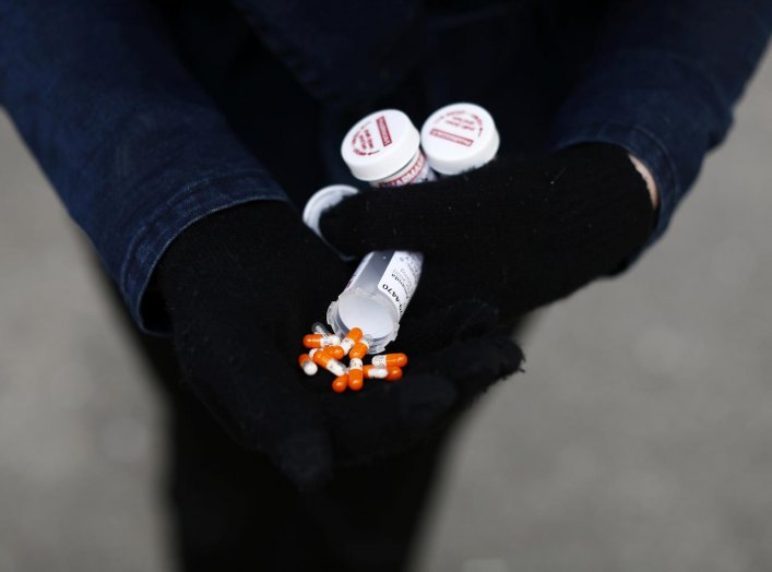 A fentanyl user displays a "safe supply" of opioid alternatives, including morphine pills, provided by the local health unit to combat overdoses due to poisonous additives and to support addicts and the homeless into practicing social distancing to help s