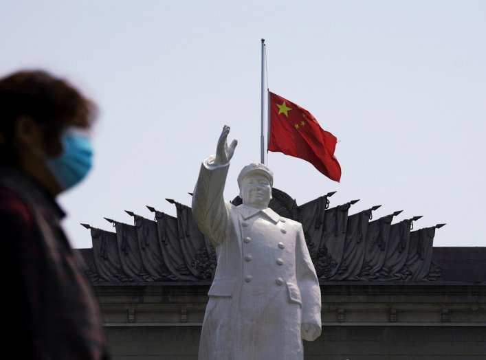 The Chinese national flag flies at half-mast behind a statue of late Chinese chairman Mao Zedong in Wuhan, Hubei province, as China holds a national mourning for those who died of the coronavirus disease (COVID-19), on the Qingming tomb-sweeping festival,