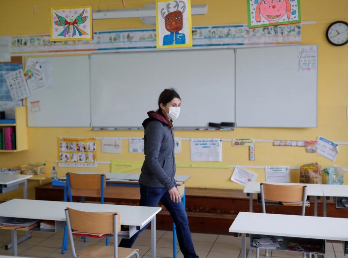 Teacher Nancie Toullec, wearing a protective face mask, walks in a deserted classroom installed to maintain social distancing in a private school open to children of health workers and workers on the coronavirus frontline in Saint-Sebastien-sur-Loire near
