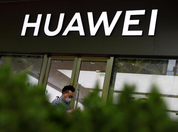 A man in a face mask walks past a Huawei shop, amid an outbreak of the coronavirus disease (COVID-19), in Beijing, China, May 18, 2020. REUTERS/Thomas Peter