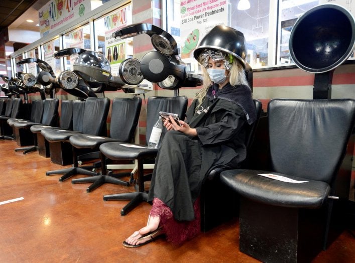 Jessica King sits under a dryer at Three-13 Salon, Spa and Boutique, during the phased reopening of businesses and restaurants from coronavirus disease (COVID-19) restrictions in the state, in Marietta, Georgia, U.S., April 24, 2020. REUTERS/Bita Honarvar