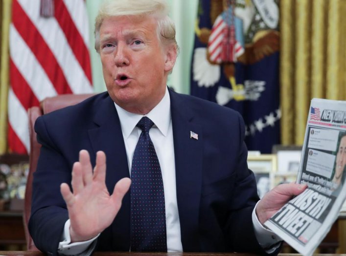U.S. President Donald Trump holds up a copy of the New York Post newspaper while speaking to reporters while discussing an executive order on social media companies in the Oval Office of the White House in Washington, U.S., May 28, 2020. REUTERS/Jonathan 