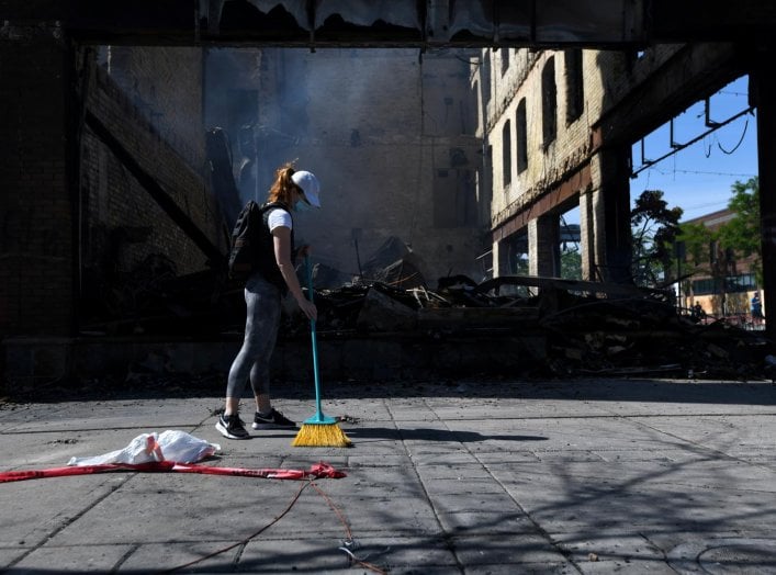 Minneapolis resident, Andrea Stoesz, cleans up outside the burned out bar Nuevo Rodeo across from the Minneapolis Police fifth precinct after the death in police custody of George Floyd in Minneapolis, Minnesota, U.S. May 31, 2020. REUTERS/Nicholas Pfosi