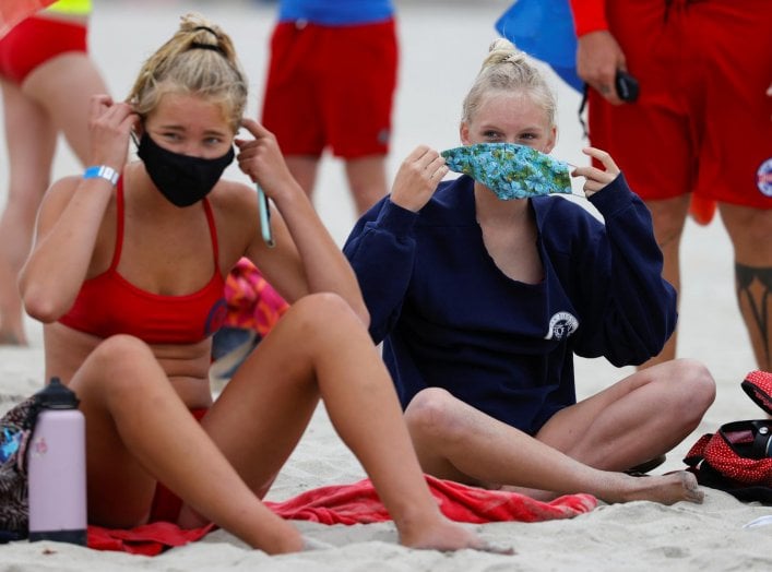 Participants apply their masks after a beach run as San Diego's Junior Lifeguard Program officially reopens with new protocols in place to comply with county health guidelines for coronavirus safety during the outbreak of COVID-19 in San Diego, California