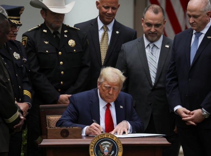 U.S. President Donald Trump signs an executive order on police reform while surrounded by law enforcement leaders during an event in the Rose Garden at the White House in Washington, U.S., June 16, 2020. REUTERS/Leah Millis