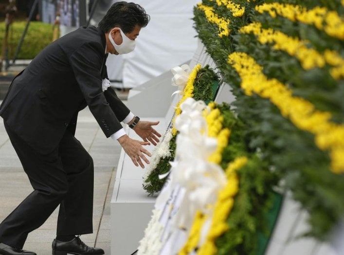 Japan's Prime Minister Shinzo Abe wearing a protective face mask, offers a wreath to the cenotaph for the victims of the 1945 atomic bombing, at Peace Memorial Park in Hiroshima, western Japan, August 6, 2020, on the 75th anniversary of the atomic bombing