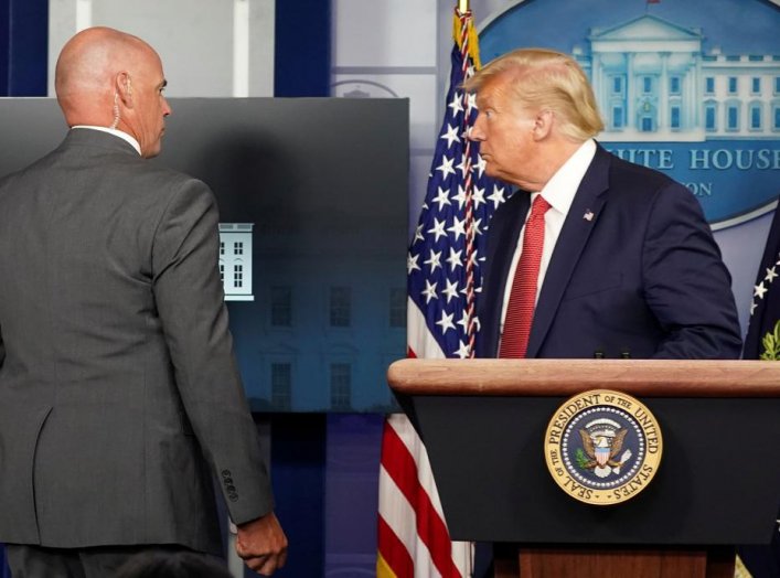 A Secret Service agent escorts U.S. President Donald Trump from a coronavirus disease (COVID-19) pandemic briefing after a shooting outside the White House in Washington, U.S., August 10, 2020. REUTERS/Kevin Lamarque