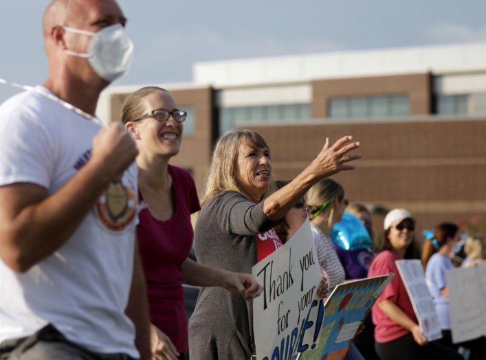 Supporters of the Cherokee County School District's decision to reopen schools to students during the coronavirus disease (COVID-19) pandemic cheer on faculty arriving to the district's headquarters, the Dr. Frank R. Petruzielo Educational Services Facili