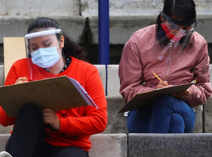 Young people wearing protective face masks and face shields maintain social distancing as a measure to contain the spread of the coronavirus disease (COVID-19) as they take the entrance exam for Mexico's National Autonomous University in the stands of Uni