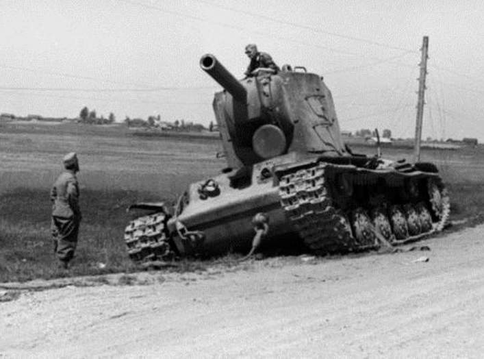 An abandoned Soviet KV-2 tank left by the roadside inspected by curious German soldiers. One KV-2, in some accounts, held up the entire 6th Panzer Division for a single day before being finally overwhelmed.