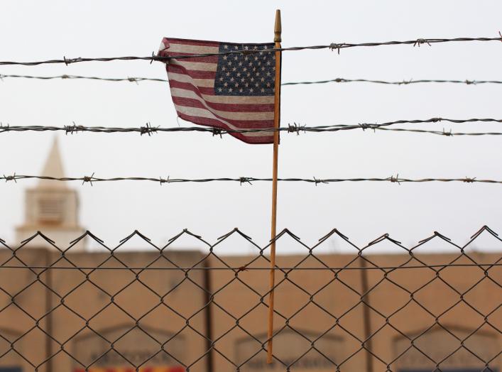 An American flag is seen behind barbed wire at the former U.S. Sather Air Base near Baghdad, Iraq December 14, 2011.