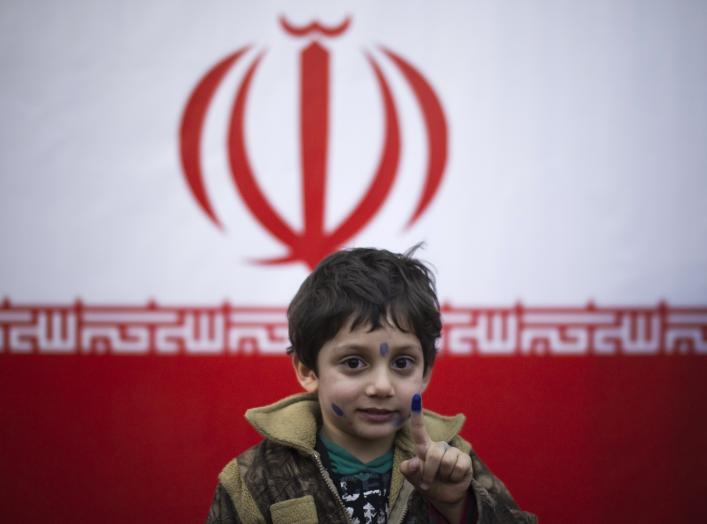 A young boy stands in front of Iran's national flag with his ink stained face and finger, symbolizing a voter who already has cast his vote, in a polling station during Iran's parliamentary election in southern Tehran March 2, 2012. REUTERS/Morteza Nikoub
