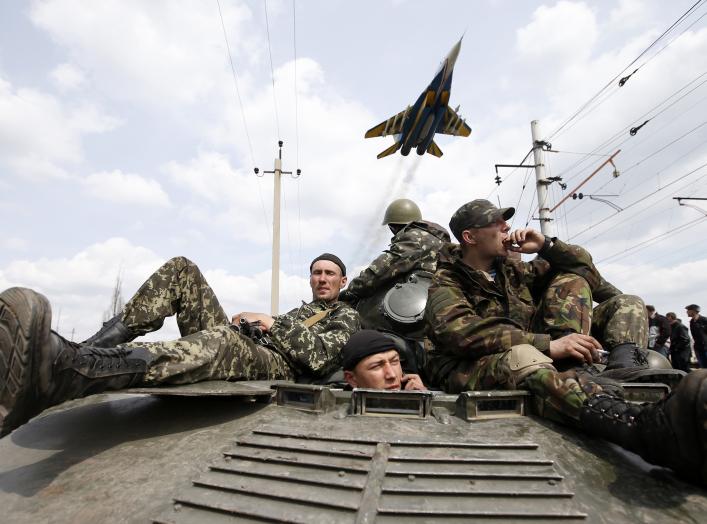 A fighter jet flies above as Ukrainian soldiers sit on an armoured personnel carrier in Kramatorsk, in eastern Ukraine April 16, 2014. Ukrainian government forces and separatist pro-Russian militia staged rival shows of force in eastern Ukraine on Wednesd
