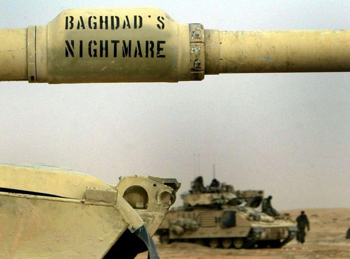 A US Army 3rd Infantry M1A1 Abrams tank with "Baghdad's nightmare" written on its cannon passes Infantry troops relaxing near the Euphrates river as hundreds of armored vehicles push towards the outskirts of Baghdad early April 6, 2003. More and more US f