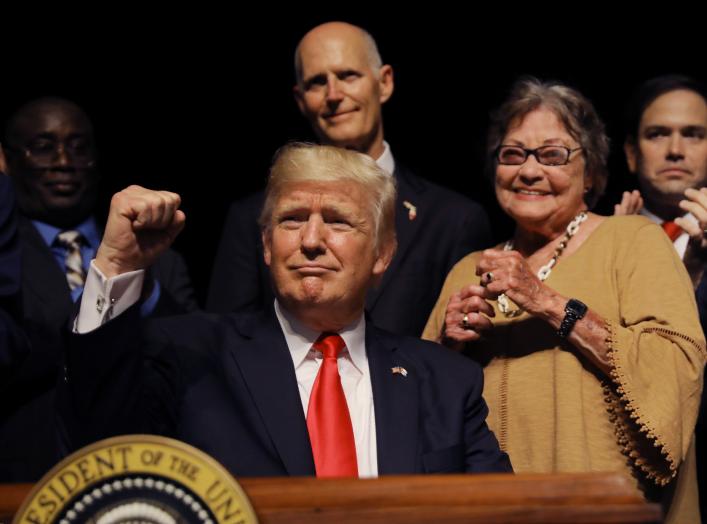 U.S. President Donald Trump thrusts his fist after signing an executive order reversing Obama administration Cuba policies as Florida Governor Rick Scott (C-rear), Cuban dissident and former prisoner Cary Roque and U.S. Senator Marco Rubio (R) look on at 