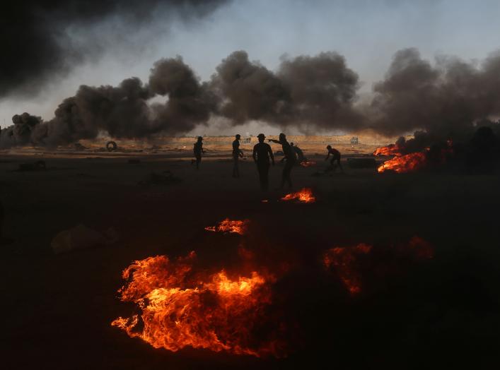 Palestinian demonstrators are seen as smoke rises from burning tires during a protest marking the 70th anniversary of Nakba, at the Israel-Gaza border in the southern Gaza Strip May 15, 2018. REUTERS/Ibraheem Abu Mustafa