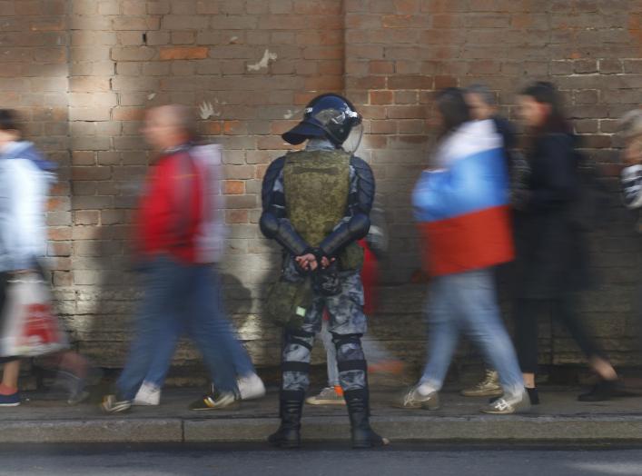 Protesters walk past an officer of the Russian National Guard during a rally against pension reforms, which envisage raising the retirement age, in St. Petersburg, Russia September 16, 2018. REUTERS/Anton Vaganov