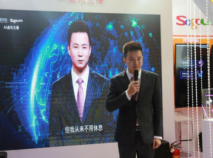 Xinhua news anchor Qiu Hao stands next to an AI virtual news anchor based on him, at a Sogou booth during an expo at the fifth World Internet Conference (WIC) in Wuzhen town of Jiaxing, Zhejiang province, China November 7, 2018. Picture taken November 7, 