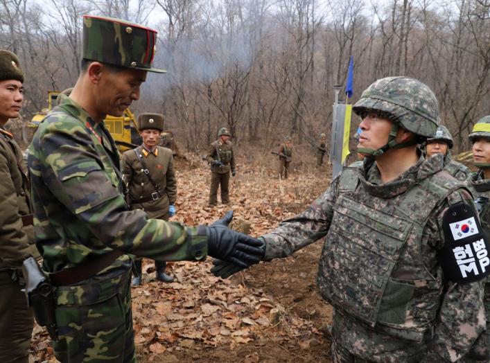 A South Korean military officer (R) and a North Korean military officer shake hands during an operation to reconnect a road across the Military Demarcation Line inside the Demilitarised Zone (DMZ) separating the two Koreas November 22, 2018. Picture taken