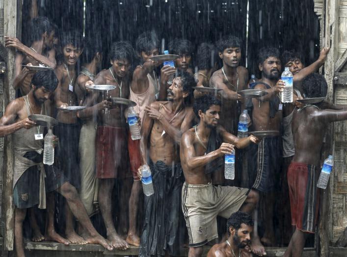 Migrants, who were found at sea on a boat, collect rainwater during a heavy rain fall at a temporary refuge camp near Kanyin Chaung jetty, outside Maungdaw township, northern Rakhine state, Myanmar June 4, 2015. Myanmar on Wednesday landed the boat with 7
