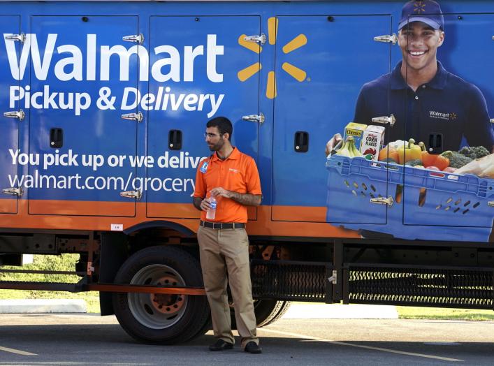 A Wal-Mart Pickup-Grocery employee waits next to a truck at a test store in Bentonville, Arkansas June 4, 2015. REUTERS/Rick Wilking