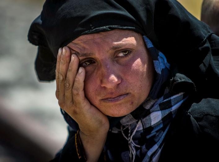 A woman reacts as she rests from walking back to Tel Abyad town, Raqqa governorate, after fleeing Maskana town in the Aleppo countryside June 16, 2015. With a string of victories over Islamic State, Syria's Kurds are proving themselves an ever more depend