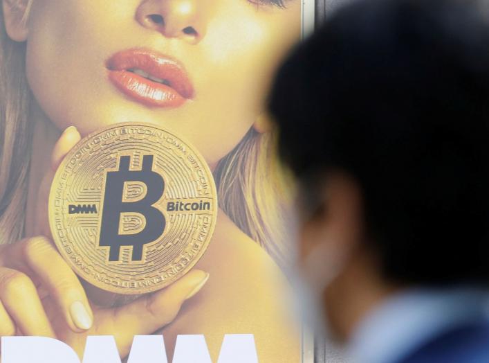 A man stands near an advertisement of a cryptocurrency exchange in Tokyo, Japan March 30, 2018. Picture taken March 30, 2018. REUTERS/Toru Hanai