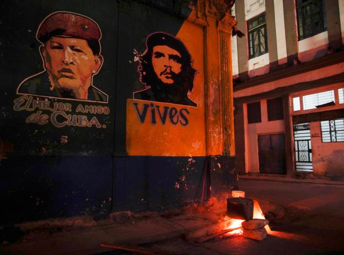 Images depicting Venezuela's late president Hugo Chavez (L), with words that read "The best friend of Cuba", and late revolutionary hero Ernesto "Che" Guevara are seen over a pot of caldosa, a typical Cuban stew during celebrations of the 59th anniversary