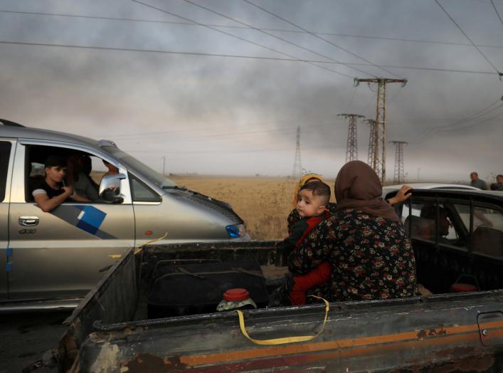 A woman with a baby sits at a back of a truck as they flee Ras al Ain town, Syria October 9, 2019. REUTERS/Rodi Said TPX IMAGES OF THE DAY