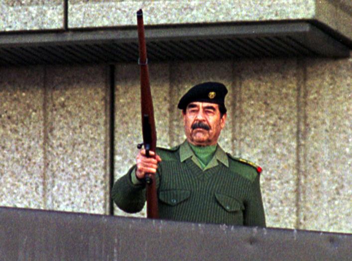 President Saddam Hussein fires a rifle in the air as he salutes Iraqi volunteers who have offered to fight with Paleastinians against Israel troops during a military parade in Baghdad on November 20, 2000. Almost two million men, women and teenagers, some