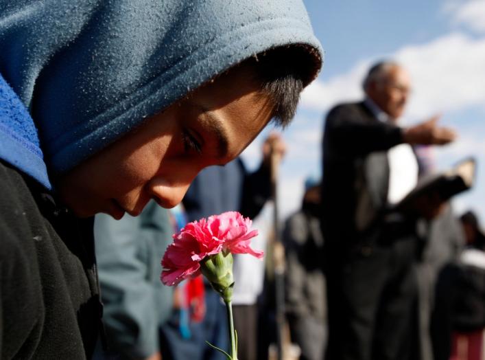 A boy holds a flower during the funeral of 16-year-old Karina Ivette Delgado in Ciudad Juarez February 3, 2011. Delgado was killed in a crossfire between suspected car thieves and federal agents on Sunday, according to local media.  REUTERS/Gael Gonzalez 