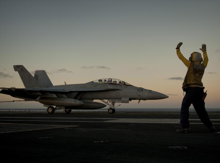 U.S. Navy Aviation Boatswain's Mate 3rd Class Tilford Breedlove signals to the pilot of an F/A-18F Super Hornet aircraft, with the Strike Fighter Squadron 22, during an arrested landing on the flight deck of aircraft carrier USS Carl Vinson (CVN-70) in th