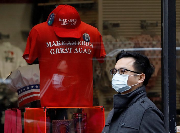 A man in a surgical mask walks by goods for sale emblazoned with U.S. President Donald Trump's 2016 campaign slogan "Make America Great Again", after more cases of coronavirus were confirmed in New York City, New York, U.S., March 10, 2020. REUTERS/Andrew