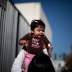 A woman plays with a baby as they wait to go into a "Back-to-School" giveaway at the Fred Jordan Mission in Los Angeles, California October 6, 2011.