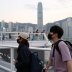 People with protective masks walk in front of Hong Kong's skyline, following the novel coronavirus disease (COVID-19) outbreak, China March 23, 2020. REUTERS/Tyrone Siu
