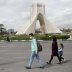 A family wear protective face masks and gloves, amid fear of coronavirus disease (COVID-19), as they walk by the iconic Freedom Square, in Tehran, Iran March 26, 2020. WANA (West Asia News Agency)/Ali Khara via REUTERS