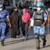 Veiled Muslim women walk past members of Rapid Action Force (RAF) patrolling a neighborhood during a lockdown in the area after dozens of men were taken to a quarantine facility amid concerns about the spread of coronavirus disease (COVID-19)