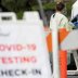 A health worker in protective gear hands out a self-testing kit in a parking lot of Rose Bowl Stadium during the global outbreak of the coronavirus disease (COVID-19), in Pasadena, California, U.S., April 8, 2020. REUTERS/Mario Anzuoni